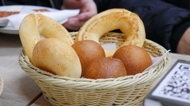 A woven basket of golden buñuelos and Colombian bread rings on a café table